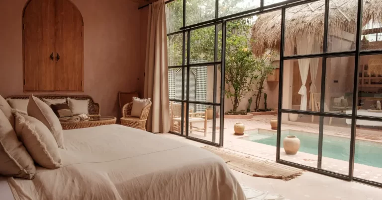 Serene terracotta-walled villa room with black-framed glass doors opening onto a tranquil central pool courtyard in Bali.