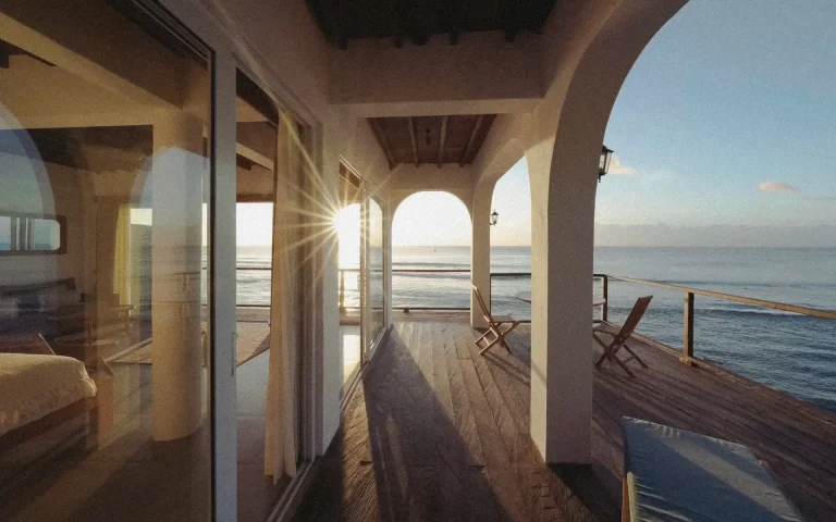 Sunlight streams through the stone arches of a balcony at Sabbia, overlooking Bali’s Bingin Beach at golden hour.