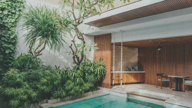 open air bali villa with wood interiors, poolside swing, and lush tropical greenery