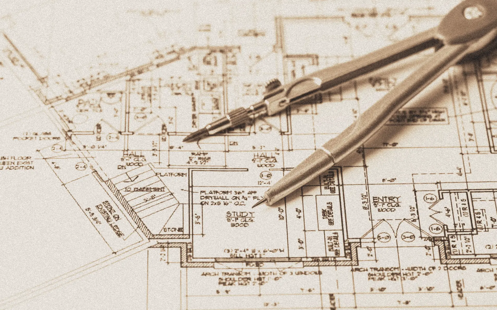 Architectural blueprints with a silver compass resting on top.