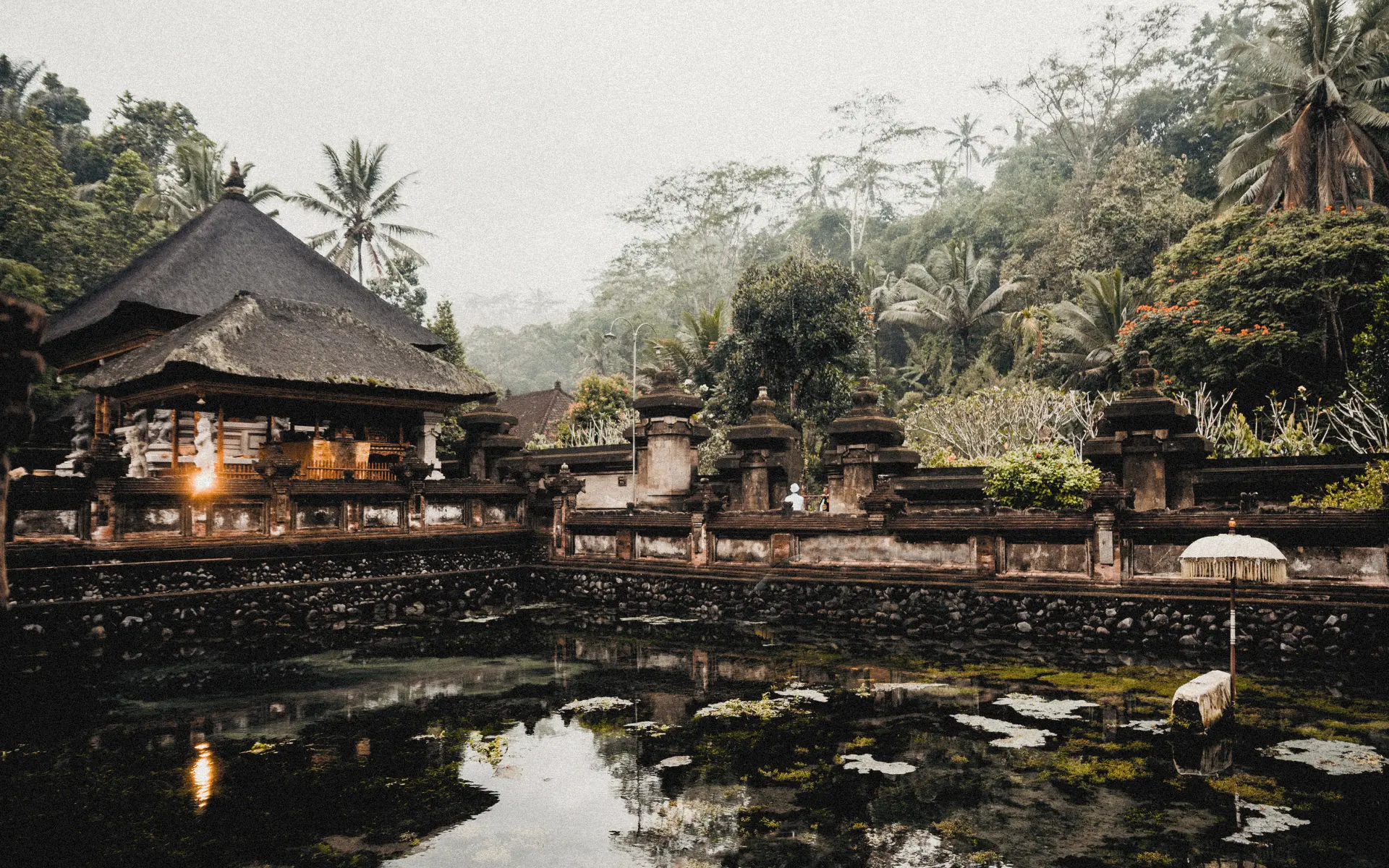 Moss-covered Balinese heritage compound behind a pond.