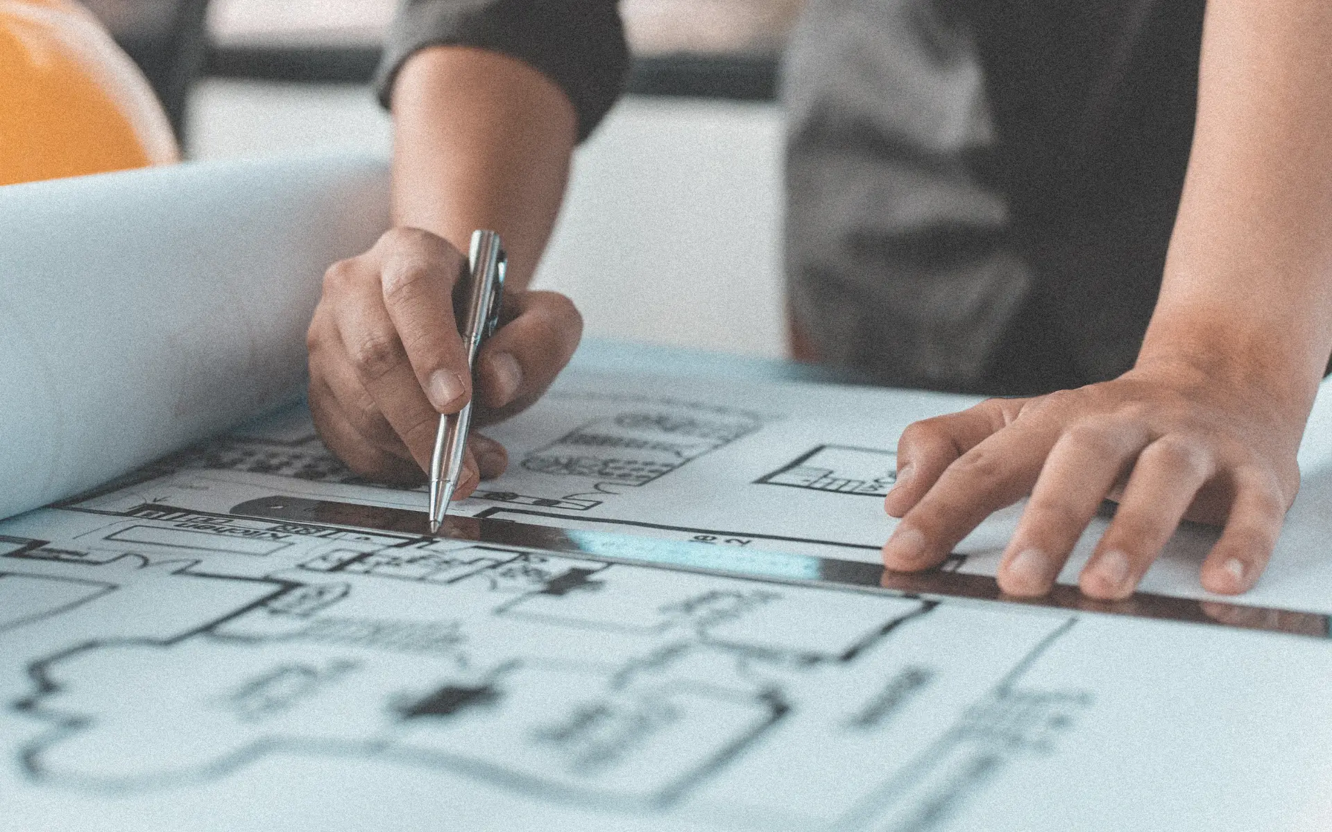 Architect using a ruler and pen while working on building plans.