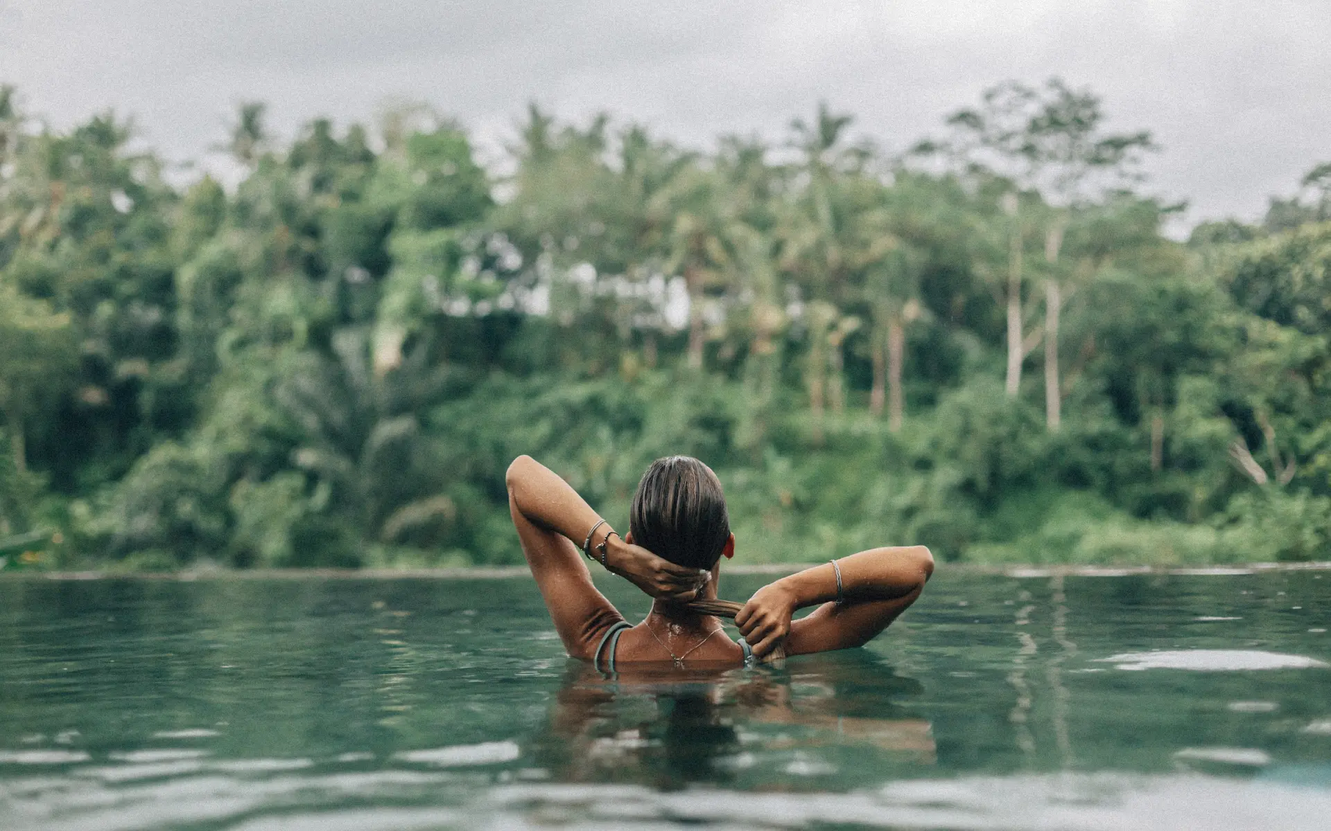 Woman in infinity pool overlooking Bali rice fields jungle backdrop villa rental experience
