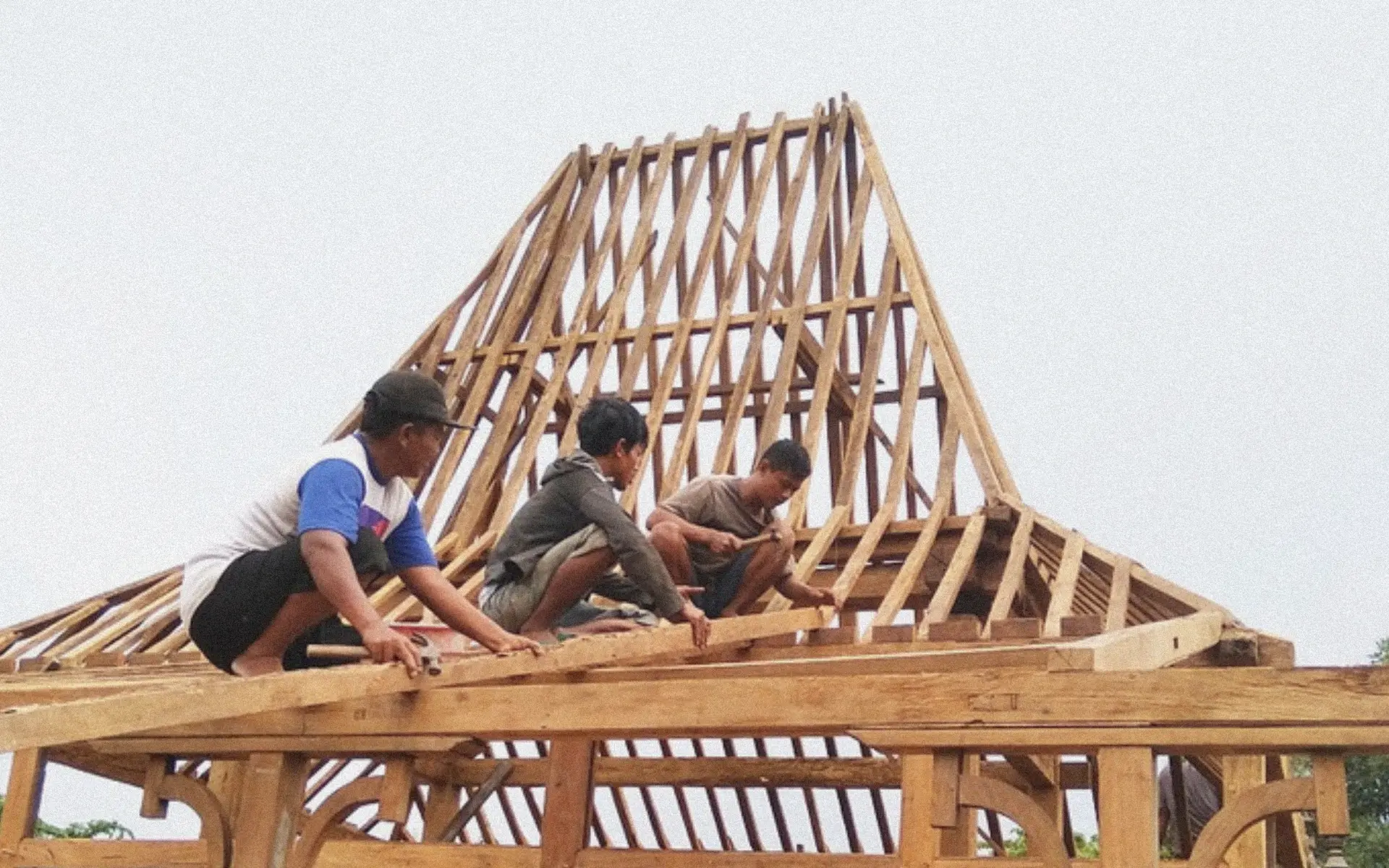 Indonesian workers assembling a traditional joglo roof frame in Bali.