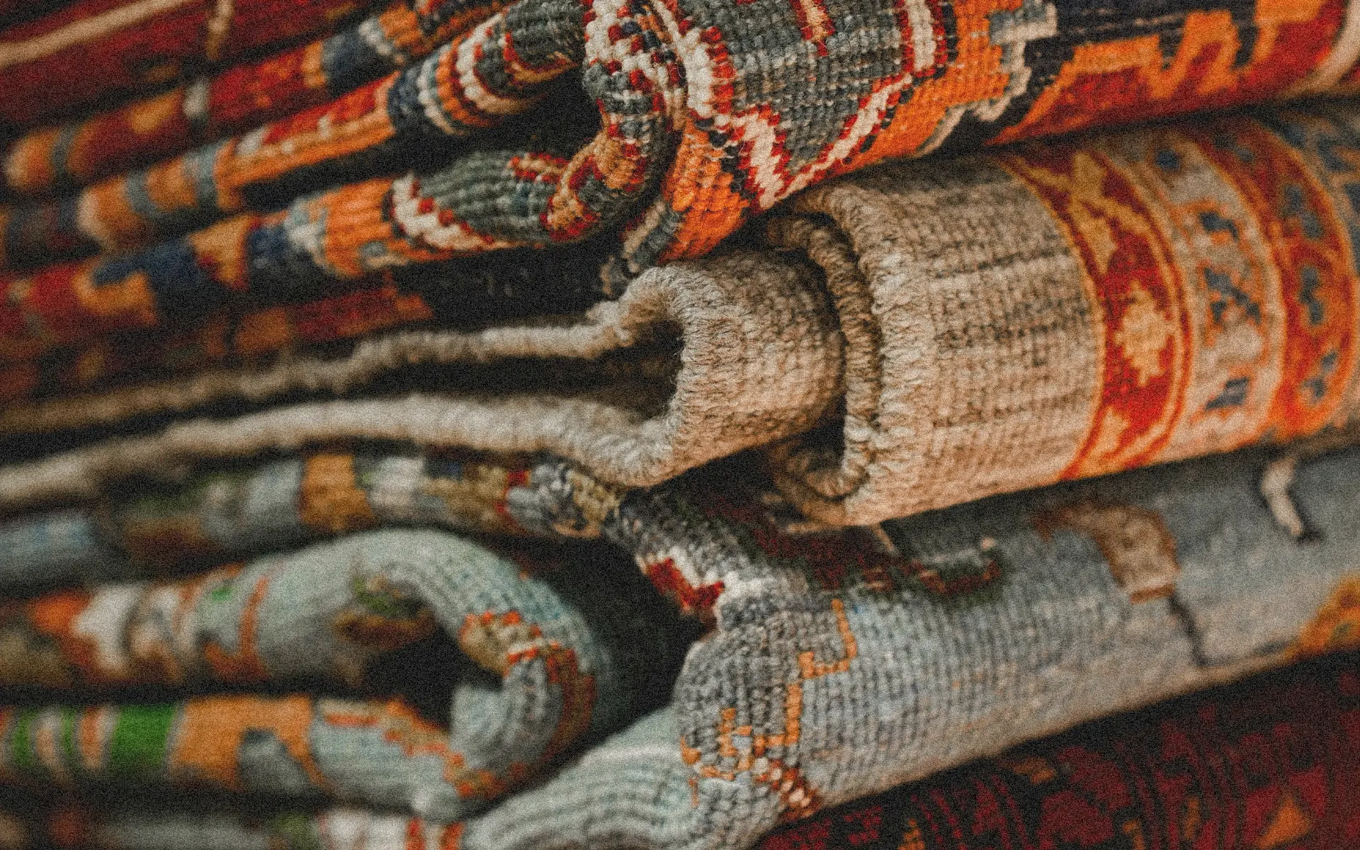 Close-up of stacked colorful exotic rugs with detailed weave and patterns