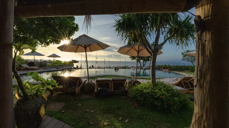 Cliffside pool at Mu Bali in Bingin with sunburst through umbrellas and Impossibles surf view