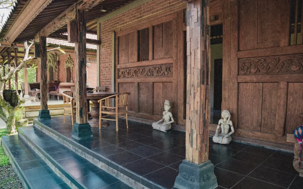 Traditional Balinese compound with wooden structures, tiled roofs, and outdoor patios before renovation.