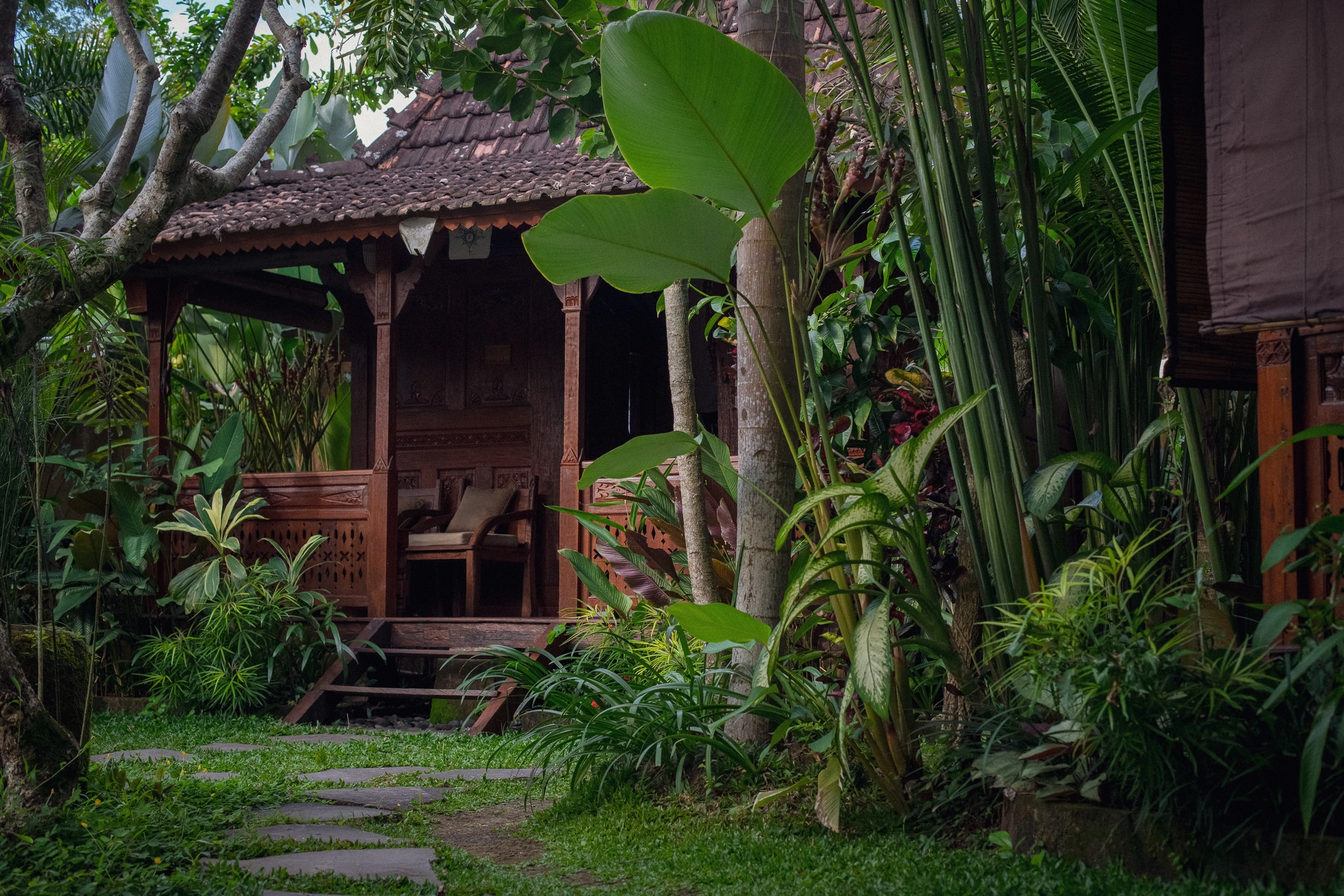 Wooden villa patio at Madani Antique Villas surrounded by lush jungle plants in Ubud, Bali