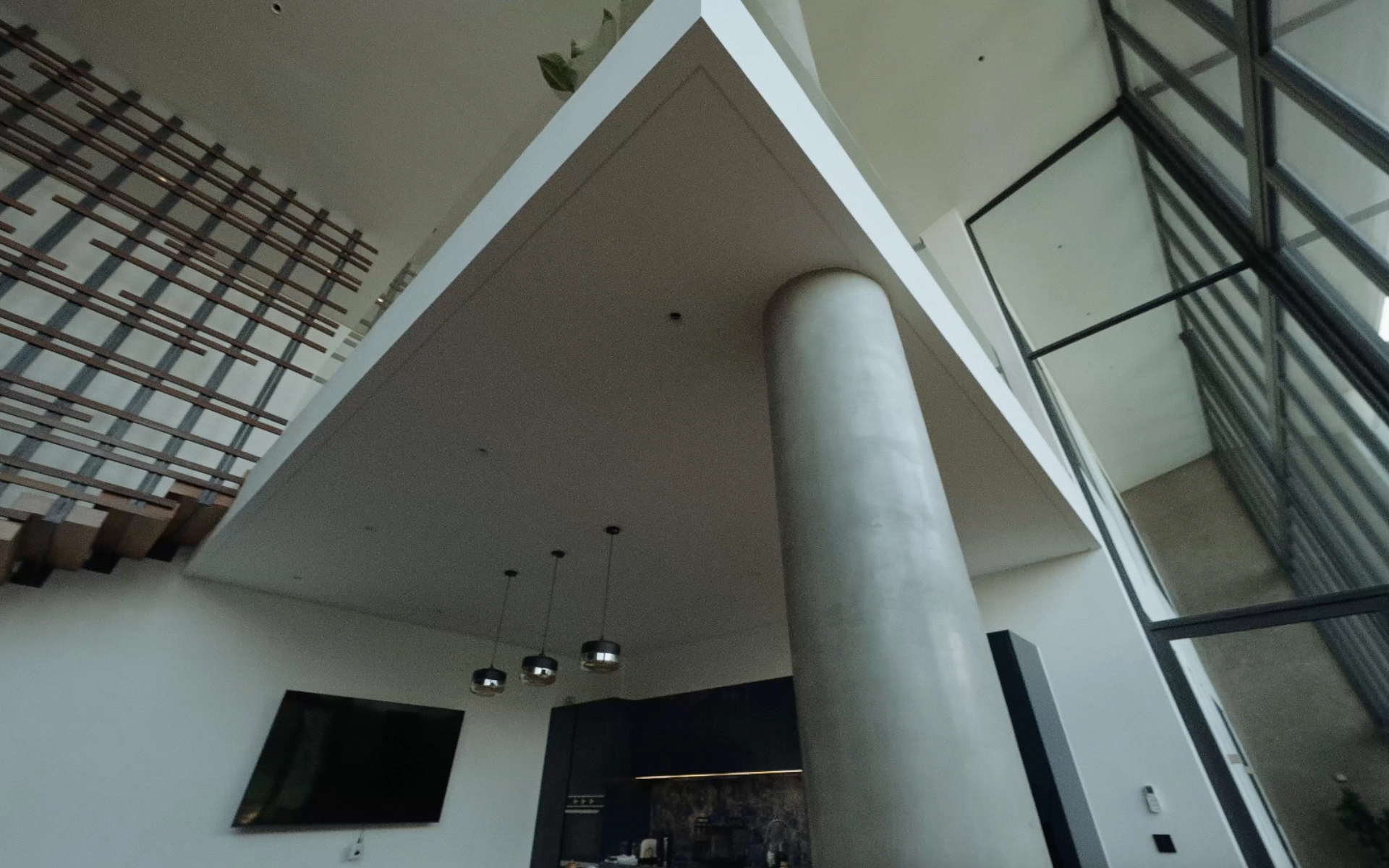 Architectural detail of a kitchen corner showing exposed concrete beam, wood finishes and floating stairs.