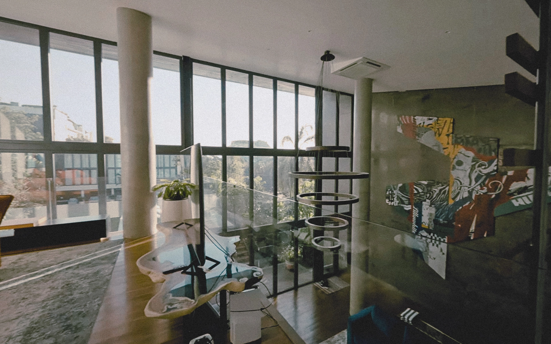 View from the upper balcony showing concrete beams, large windows and an art installation by Rangga Maulana Koto.