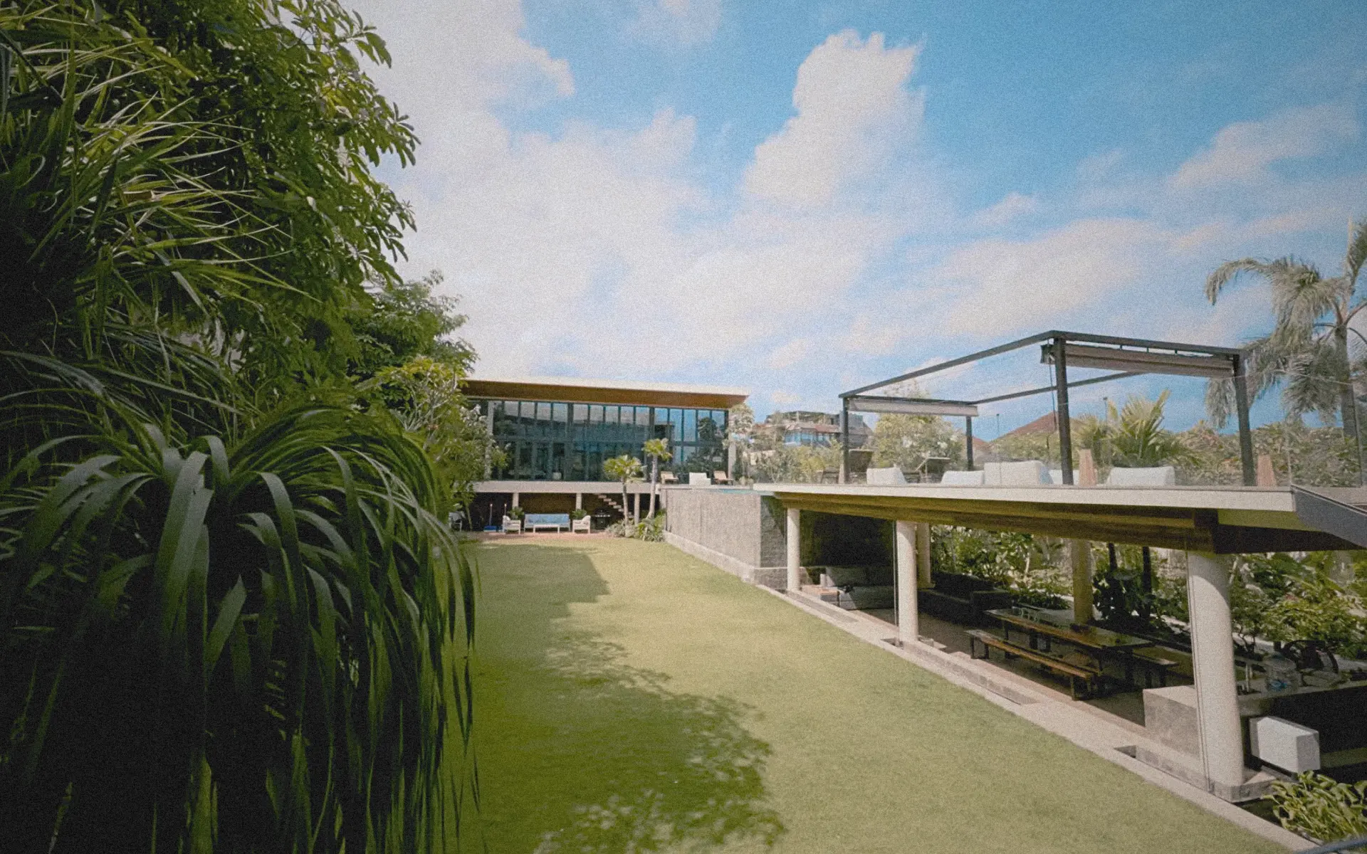 Tropical brutalist villa at The Lilly Pad with concrete volumes, pool deck, patio, and lush landscaping.