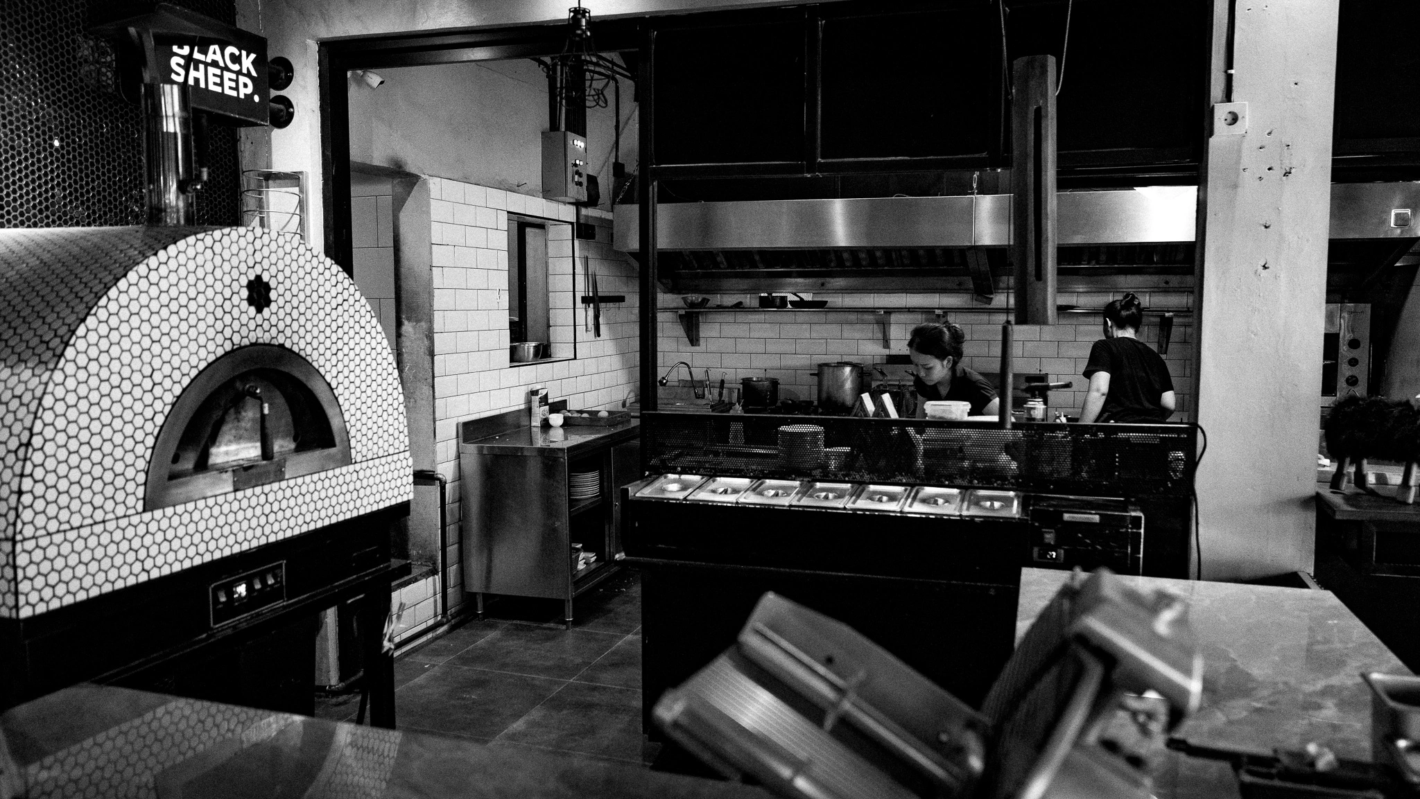 Black and white photo of the kitchen and tiled pizza oven at Black Sheep Ubud