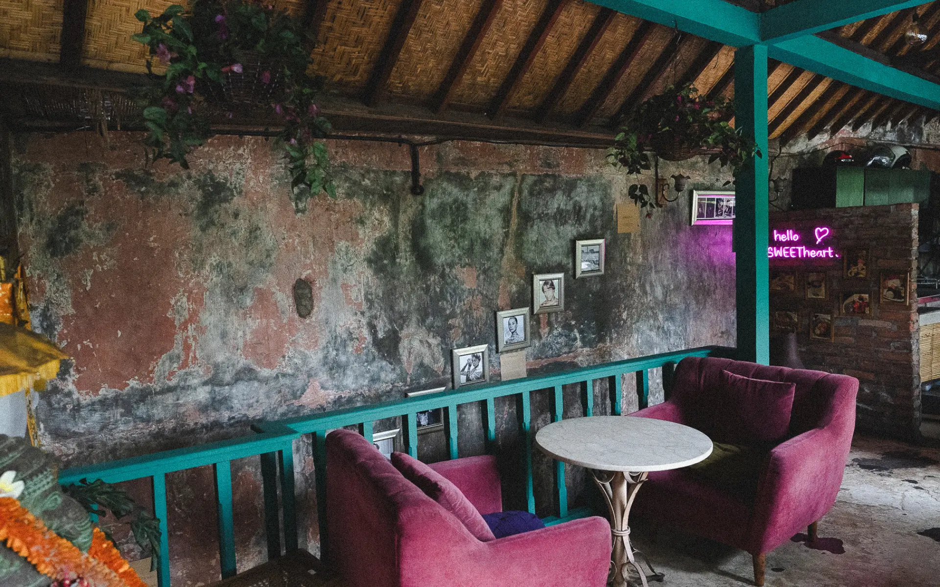 Two pink velvet chairs and a small table beneath a neon “hello sweetheart” sign at Lazy Cats Ubud, showcasing the café’s playful vintage décor.