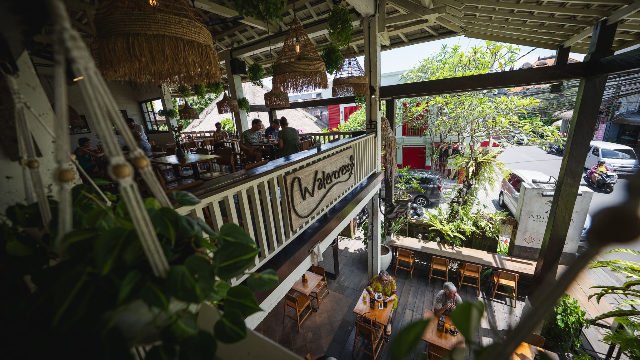 View from the upstairs balcony at Watercress Ubud of diners at tables and hanging plants