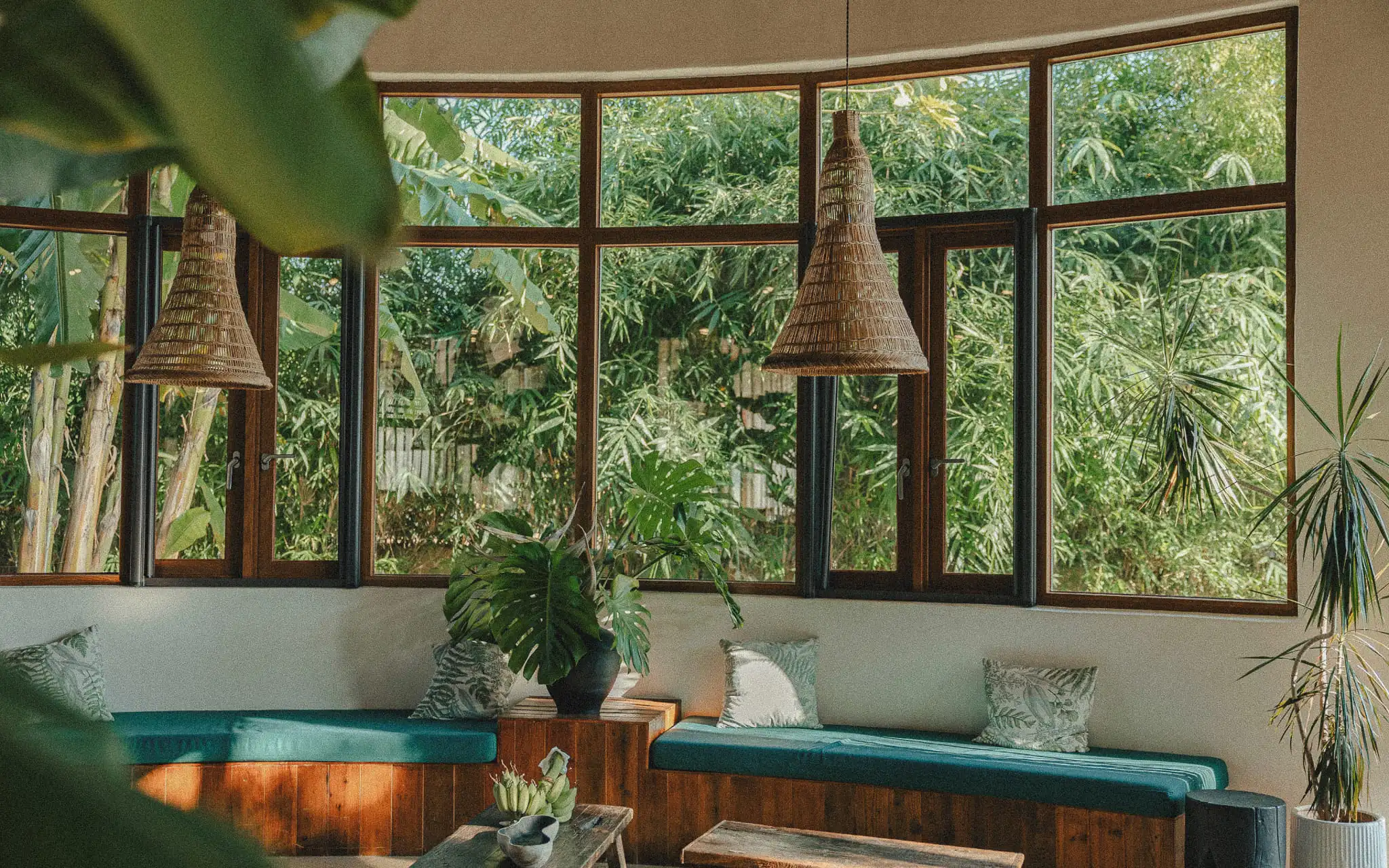 Boho tropical window seat with green cushions overlooking bamboo garden