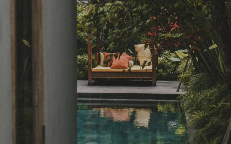 Poolside daybed surrounded by lush tropical planting in a Bali garden.