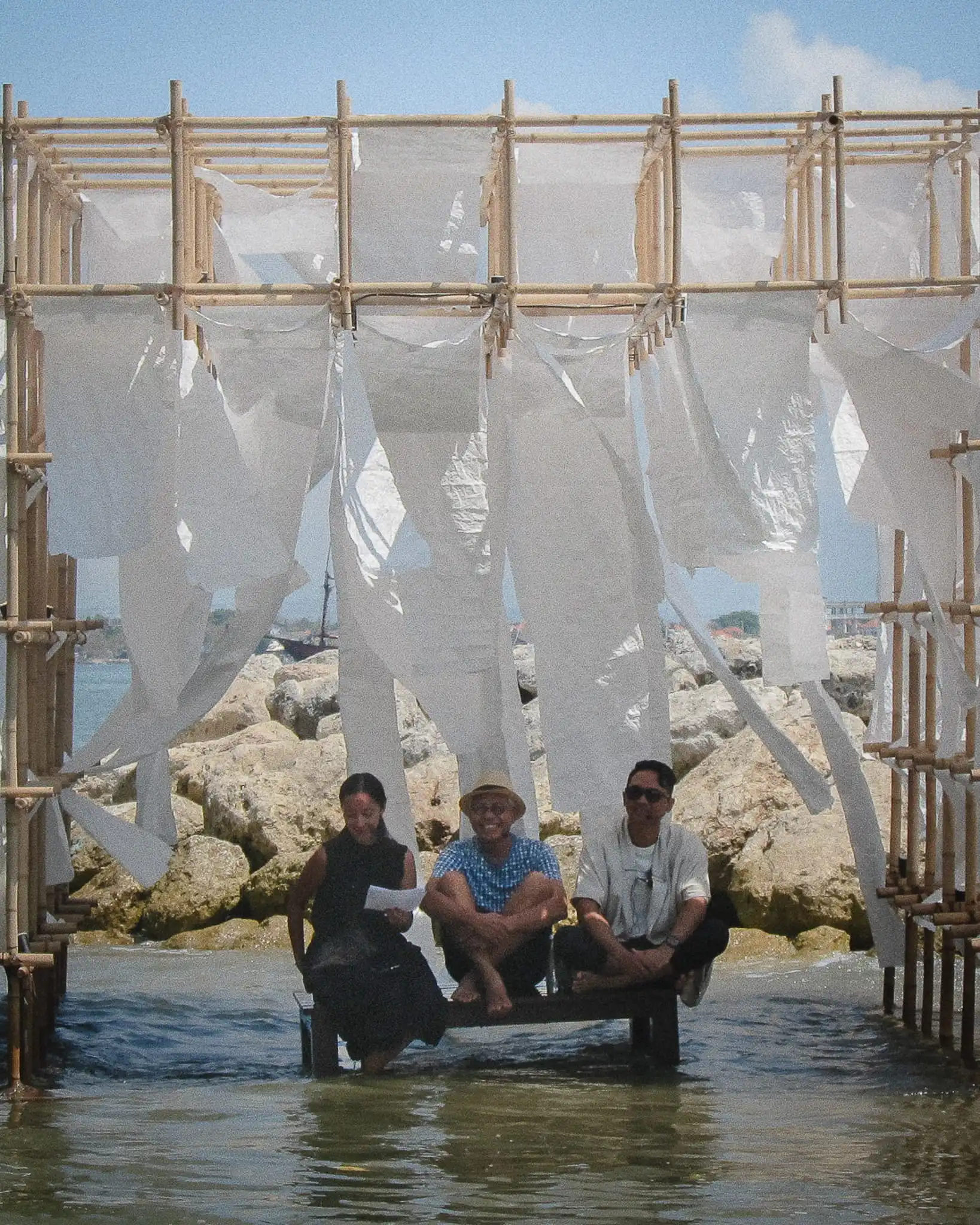 Popo Danes, I Ketut Dirgantara and Raina Alonge seated on the flooded beachfront stage at Jia Curated