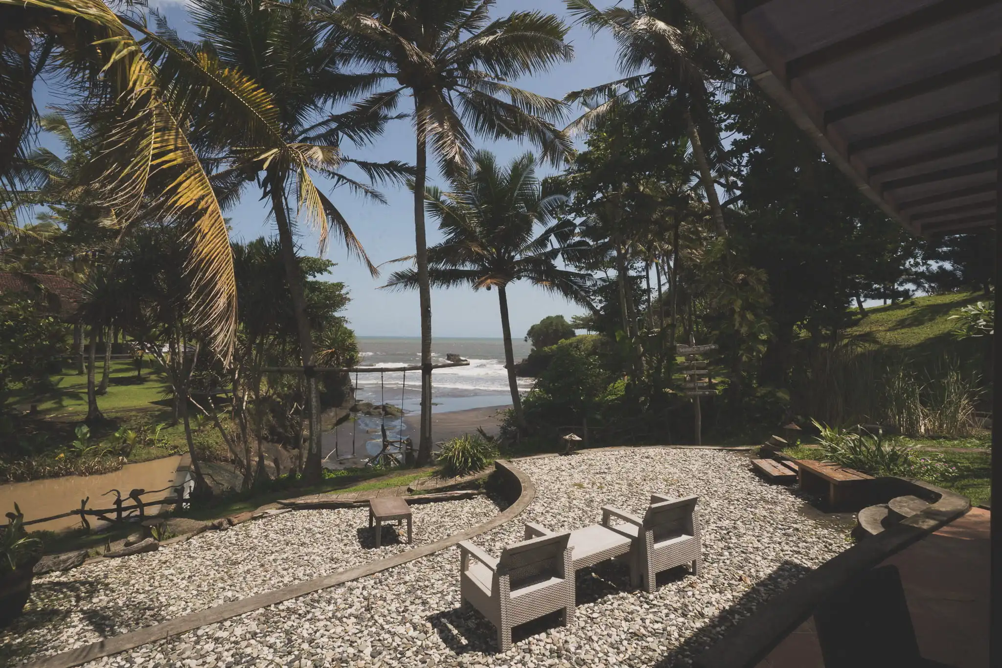 Building, chairs and swing on a green coastal edge beside the ocean in Bali